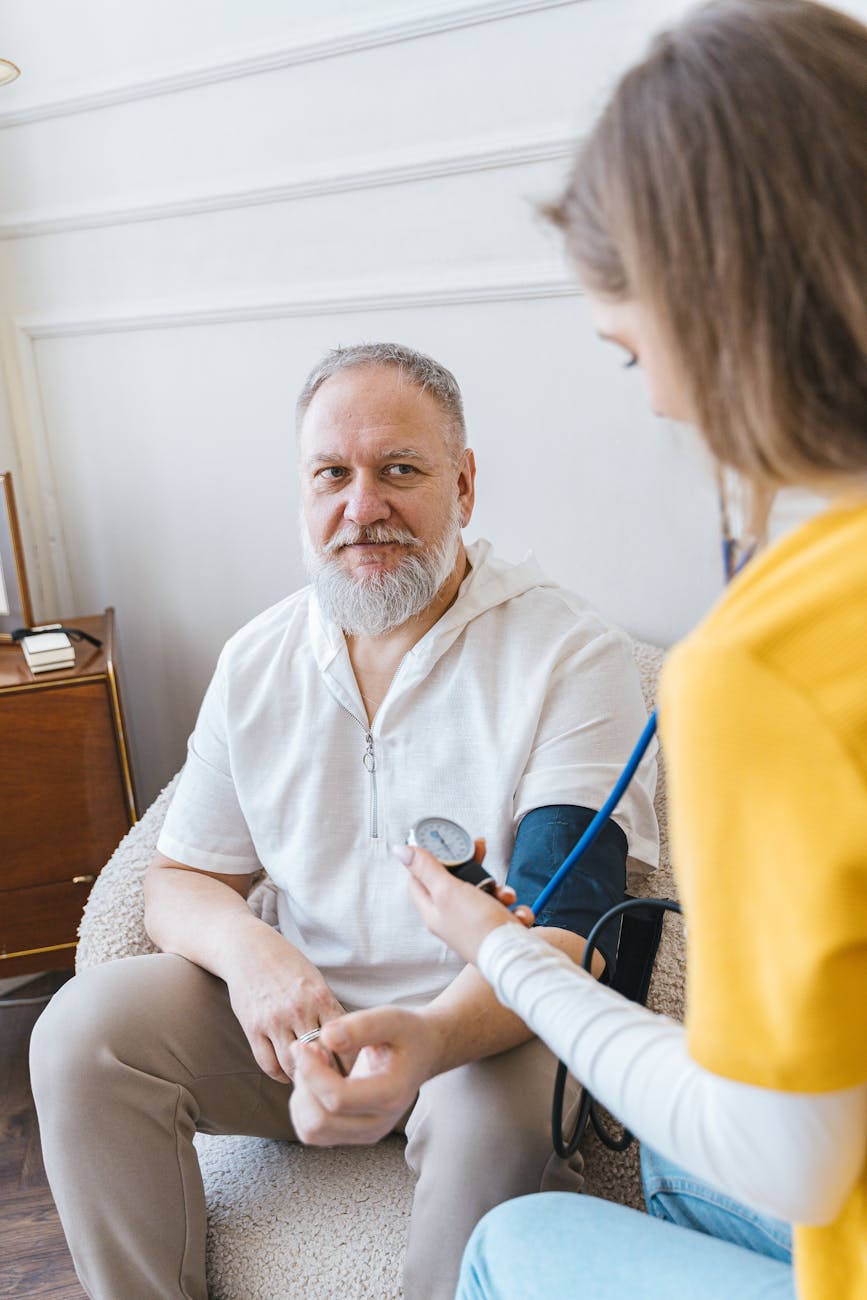 woman measuring the blood pressure of an elderly man with a blood pressure monitor